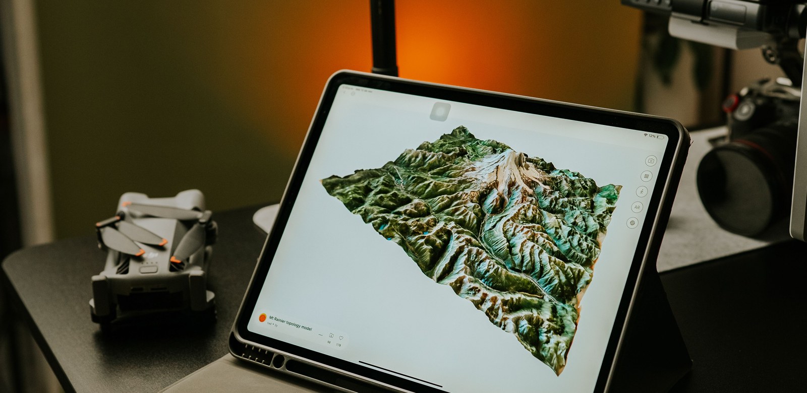 3D terrain model rendered on a tablet beside a mapping drone